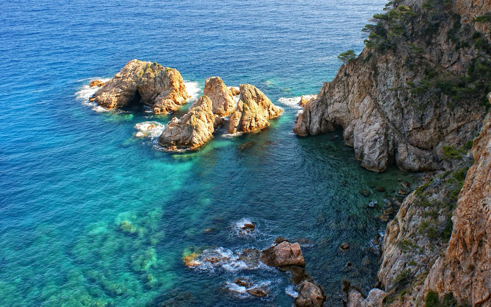 a body of water next to a rocky cliff
